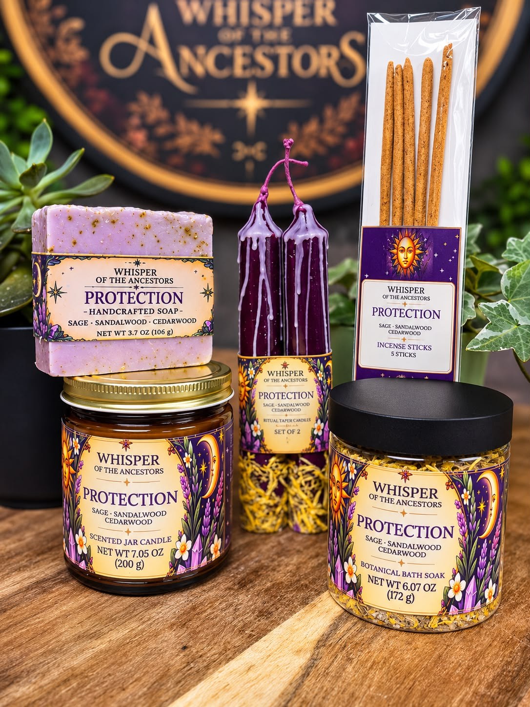 The full Protection collection — handcrafted soap, botanical bath soak, taper candles, incense sticks and jar candle in purple, gold and cream labels, arranged on a wooden table in front of the Whisper of the Ancestors seal